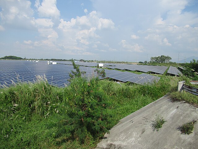 Solar panels in the Philippines surrounded by green grass in a field.